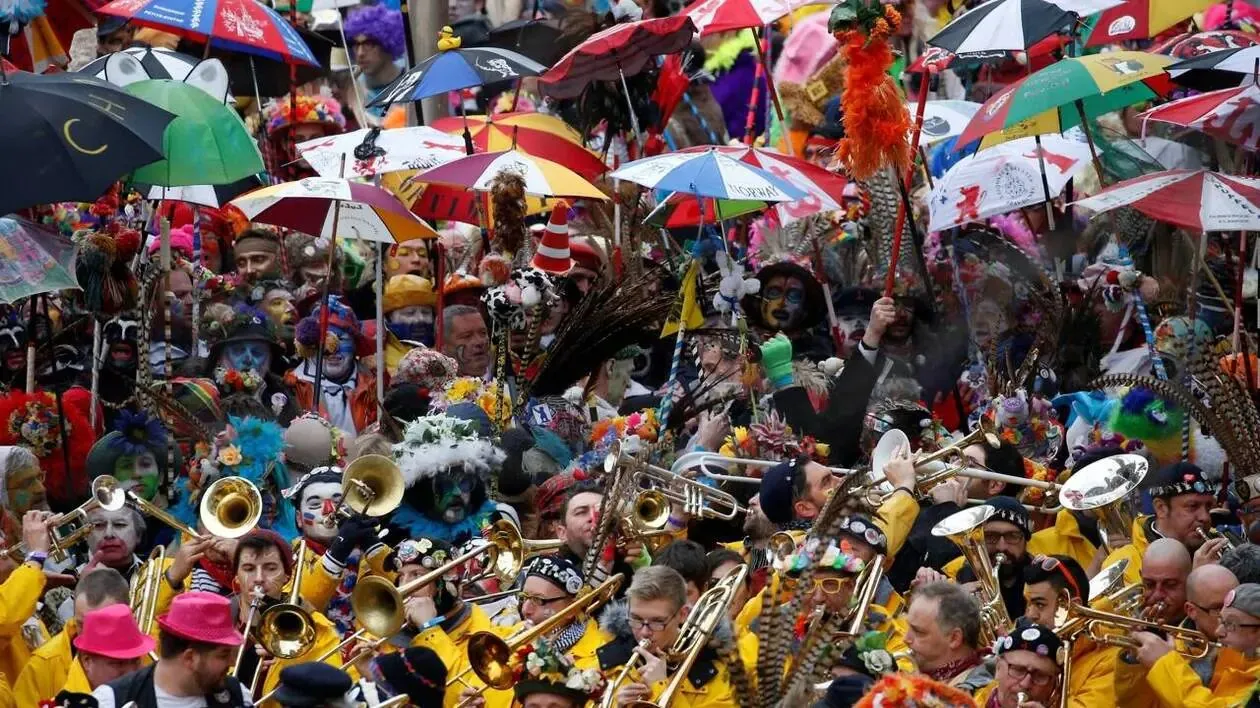 The crowd at Dunkirk carnival, umbrellas raised and yellow oilskins