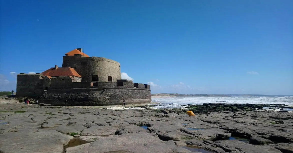 Het fort van Ambleteuse op de rotsen, bij laag water, onder een blauwe lucht