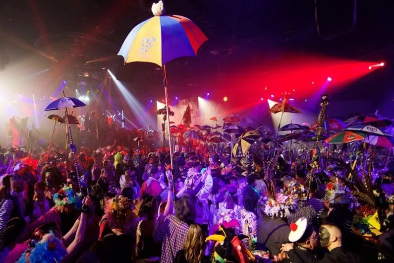 A carnival ball, umbrellas raised under the lights