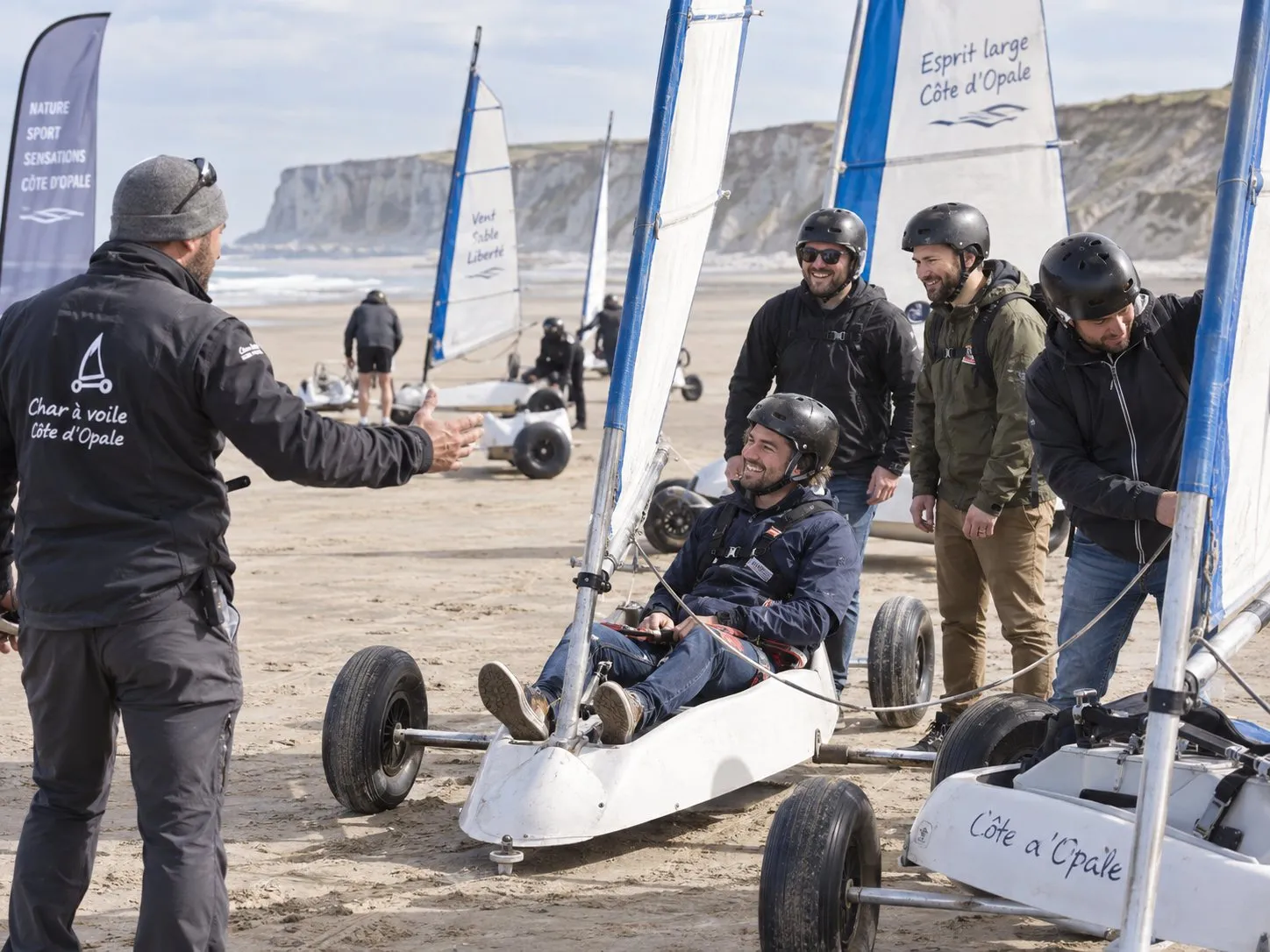 Un char à voile sur le sable, au pied des falaises
